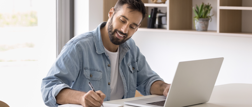 Mężczyzna siedzący przy stole, przed komputerem