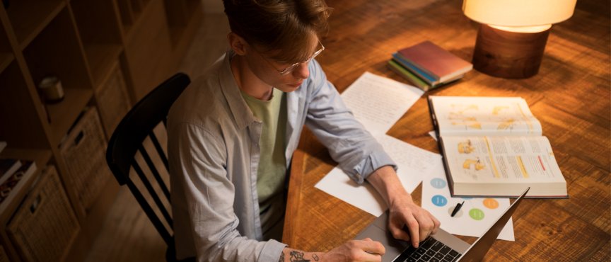 Mężczyzna siedzący przy stole, przed komputerem