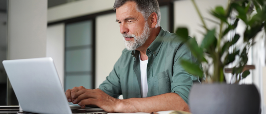 Mężczyzna siedzący przy stole, przed komputerem