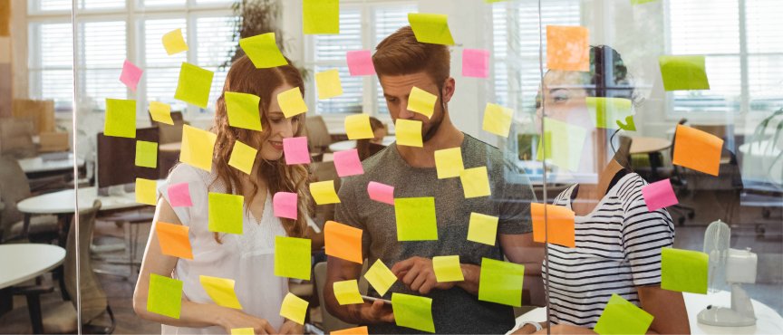 dwie osoby stoją przy przezroczystej tablicy z karteczkami