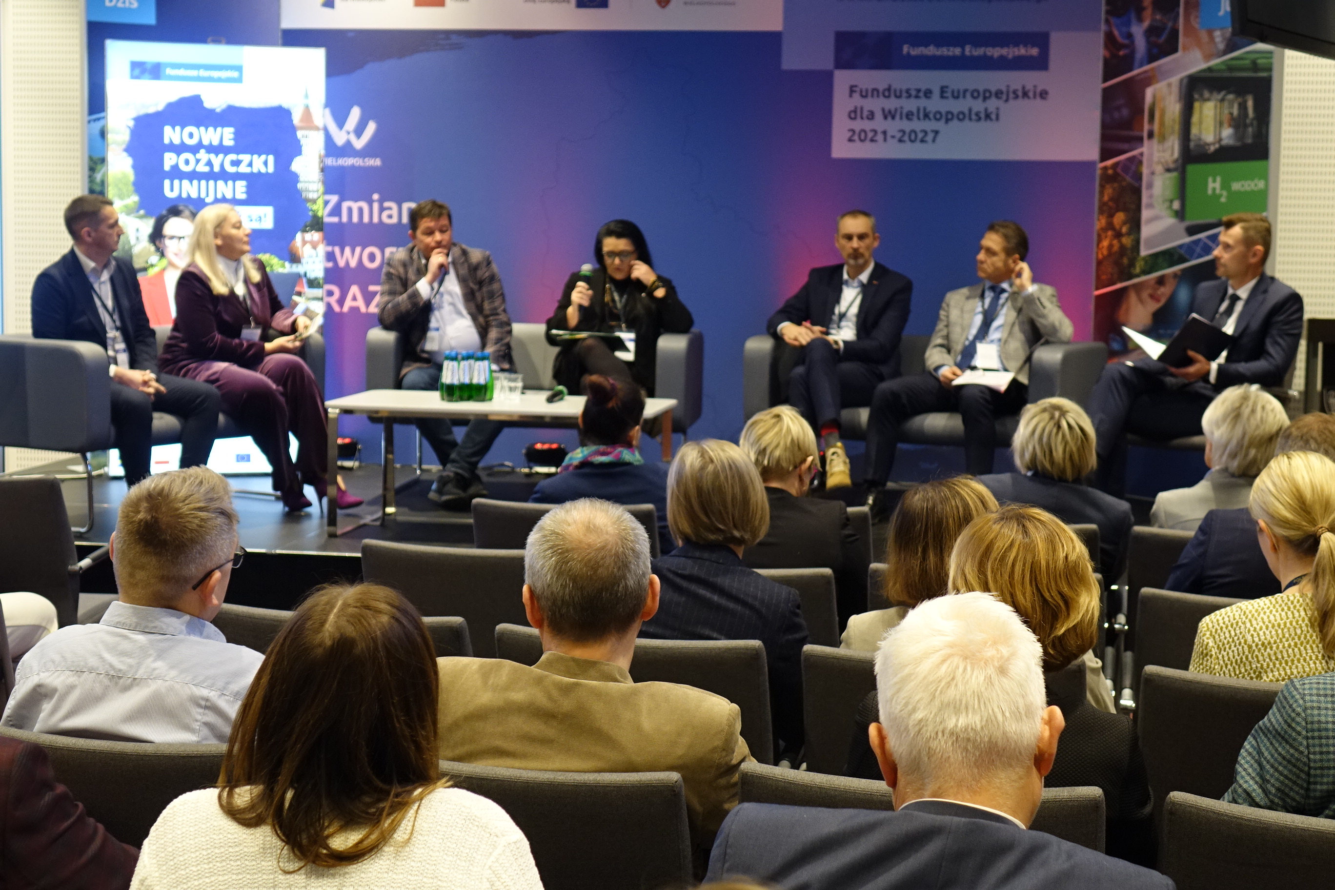 Na zdjęciu widać sześciu panelistów i osoby słuchające na widowni 