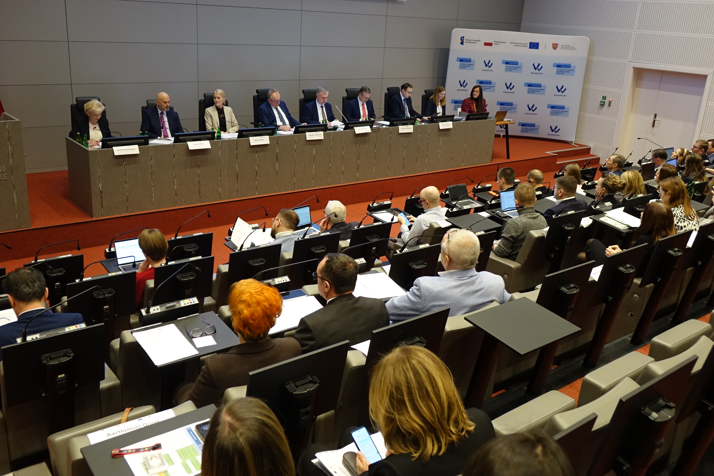 Na zdjęciu widać kilkanaście osób siedzących na widowni sali sesyjnej 